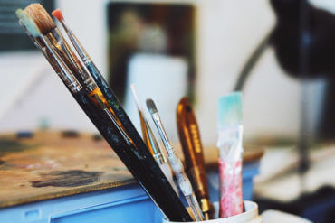 杂乱无章的艺术家工作室,在一个旧容器里放着画笔